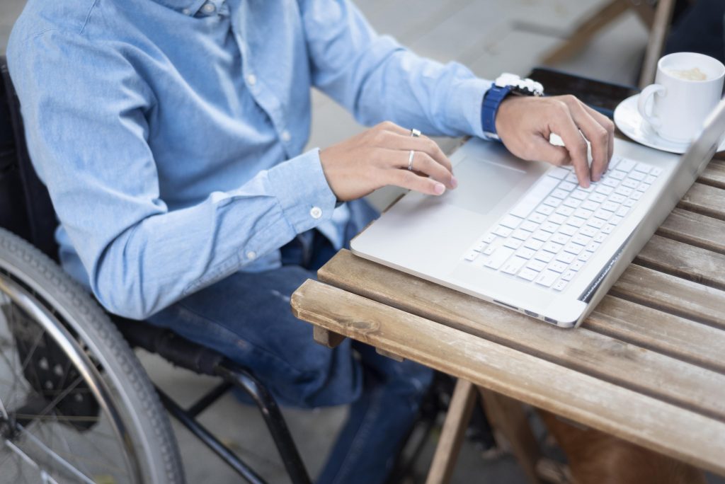 close up disabled man typing laptop