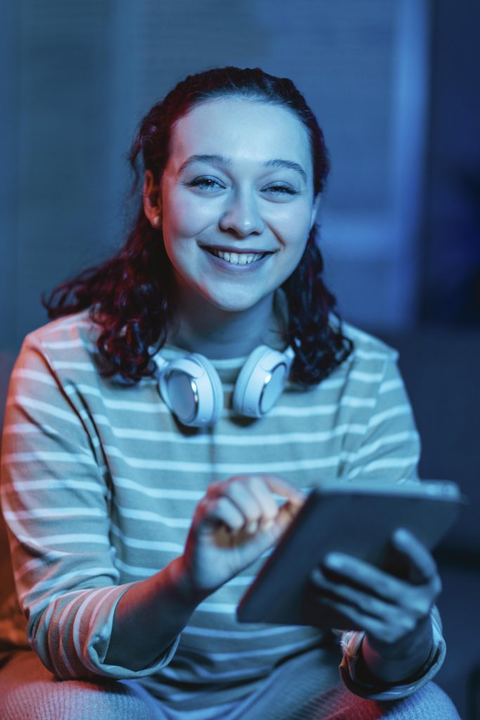 front view smiley woman home using headphones tablet