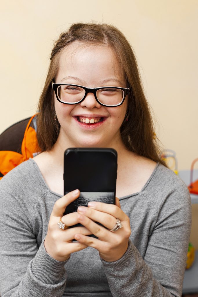 smiley girl with down syndrome holding phone