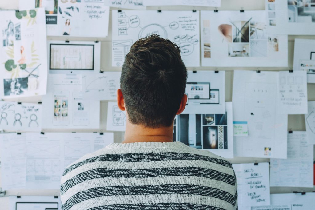 A man stands in front of a wall filled with creative ideas and plans. Ideal for innovation themes.